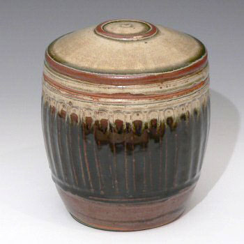 Large stoneware caddy with ash glazed lid on fluted iron glazed base.