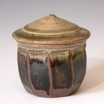 Small stoneware facetted jar with conical lid.