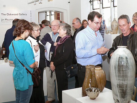 Exhibition visitors socialising, tall nuka glazed bottle in foregroun