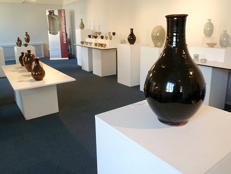 View across the exhibition, temmoku glazed Korean bottle in foreground