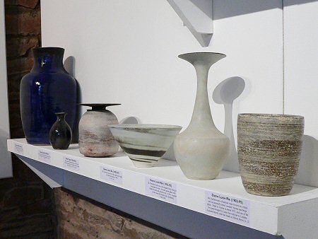 Hans Coper bottle with disk shaped rim surrounded by Lucie Rie pots