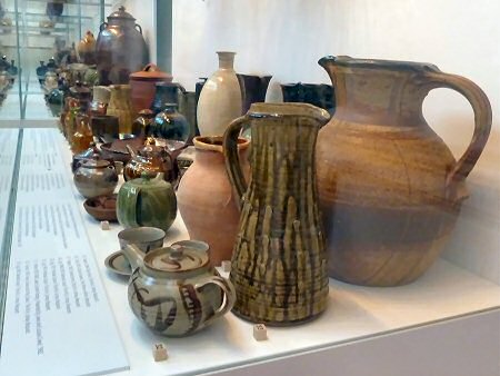 Along the bottom shelf of the wall of pots